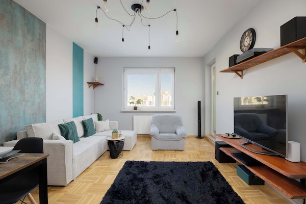 A stylish living room with a large sectional sofa and modern accents. The space feels warm and inviting with decorative elements on the wall.