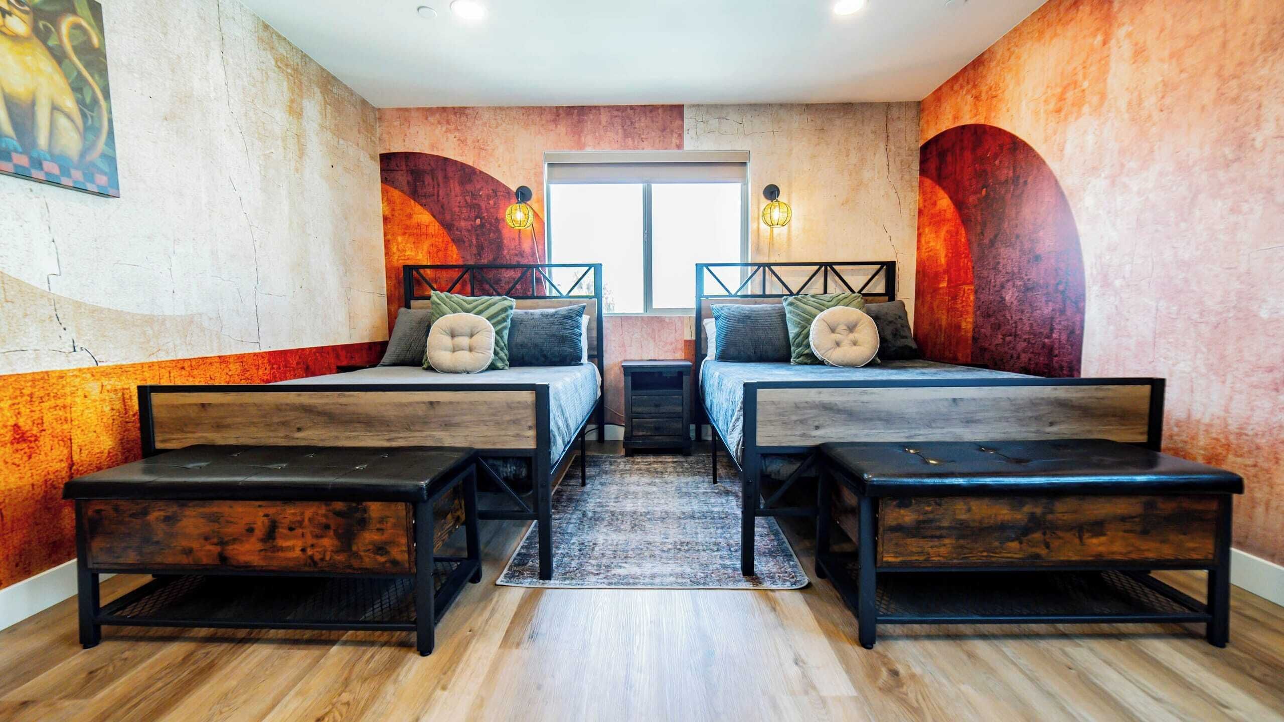 A room with two beds, a bench, and a window.