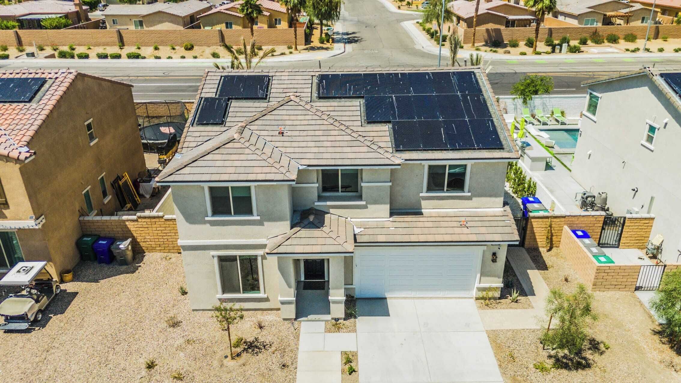 Ein zweistöckiges Haus mit Solaranlage auf dem Dach, einer Garage und einem kleinen Vorgarten mit Baum.