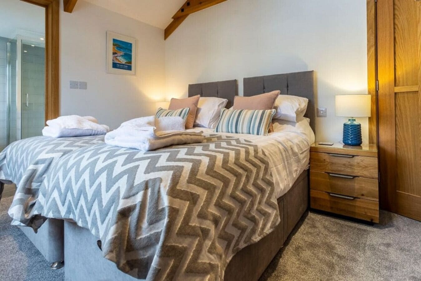 A bedroom with a bed, a nightstand, a lamp, and a wooden door.