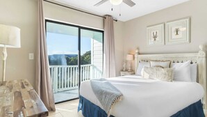 Ein Schlafzimmer mit einem großen Bett, einem Balkon mit Blick und einem Deckenventilator.