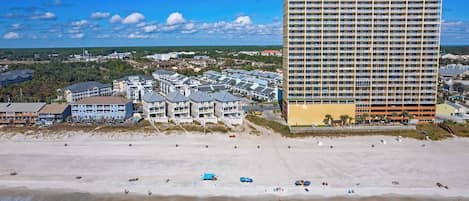 Un hotel frente a la playa con varias edificaciones, una playa arenosa y aguas turquesas cristalinas.