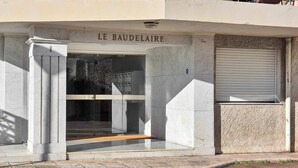 L'ingresso di Le Baudelaire, con facciata in marmo, una porta in vetro e un cartello sopra la porta.