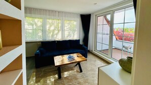 A living room with a dark blue sofa, a wooden coffee table, and a large sliding glass door leading to an outdoor area. - FeWo II Graal-Müritz Sobierajczyk (Graal-Müritz)
