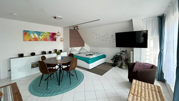 Una sala de estar moderna con comedor, sofá, televisor y escalera.