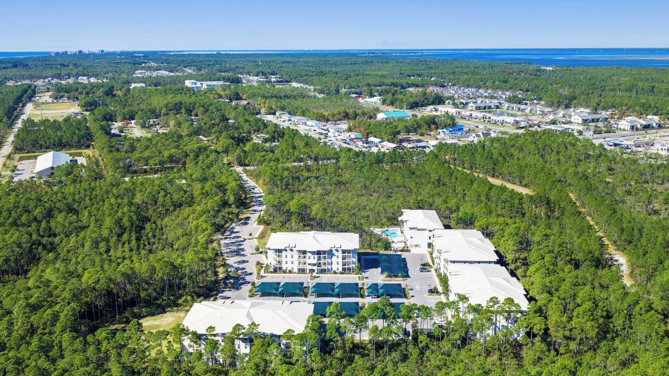 An aerial view of a resort with multiple buildings, a parking lot, and surrounding forested areas.