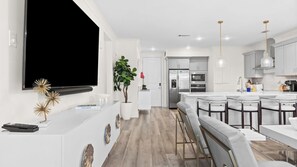 Une cuisine moderne avec des meubles blancs, un four encastré et un réfrigérateur en acier inoxydable.