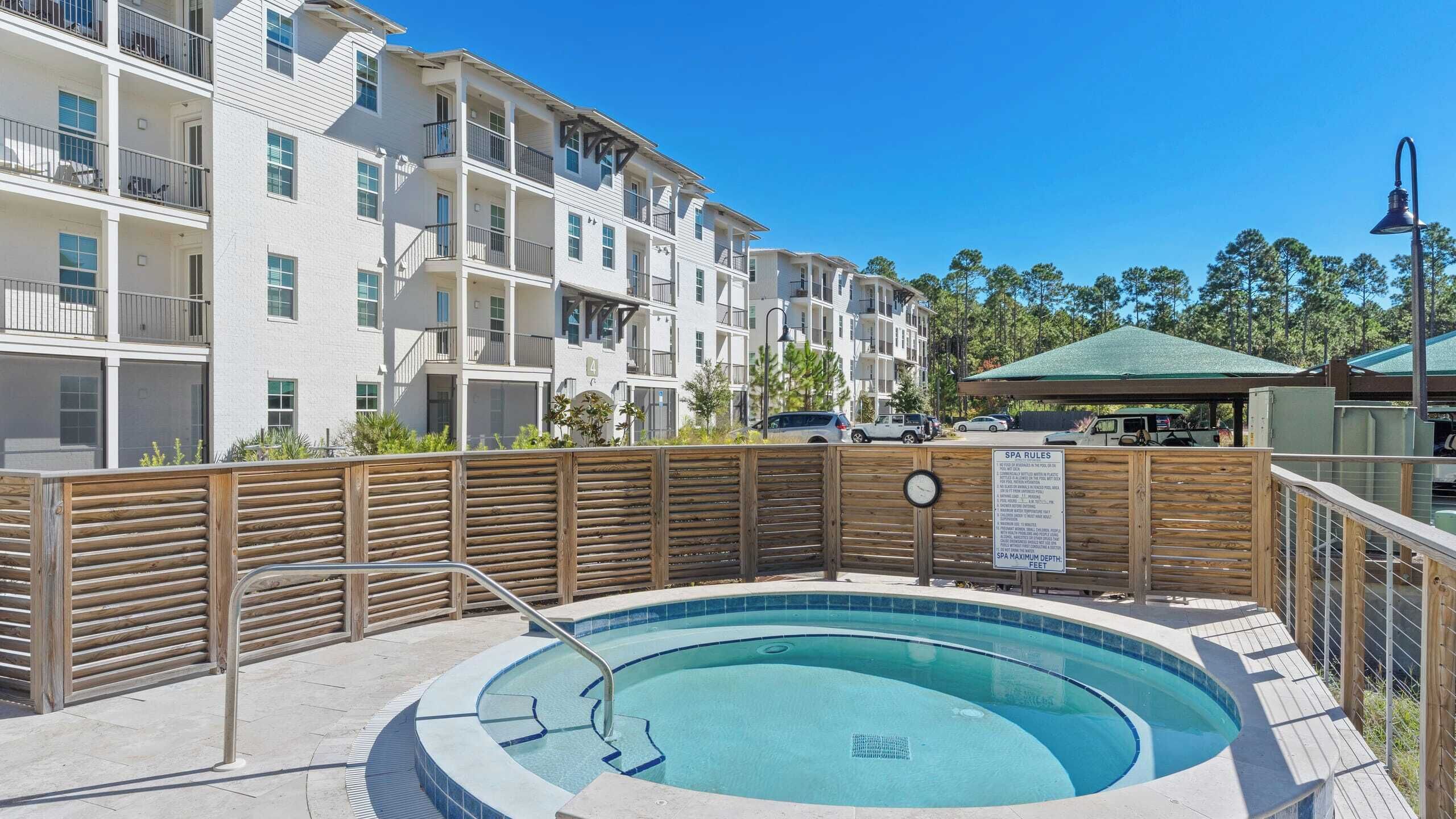 A swimming pool with a wooden deck, surrounded by a wooden fence, and a sign indicating spa rules.