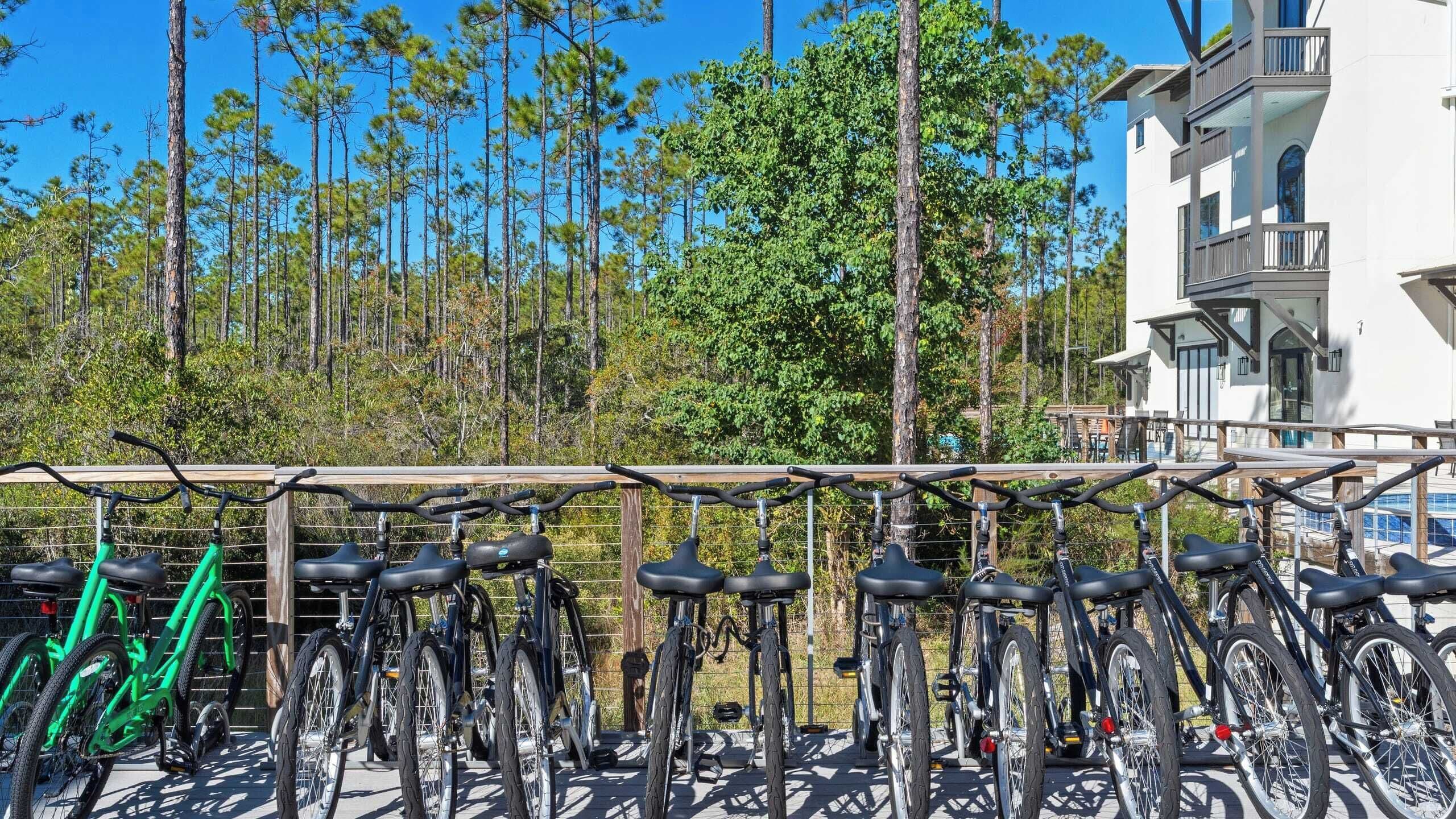 Varias bicicletas están estacionadas frente a un edificio con vista a altos árboles.