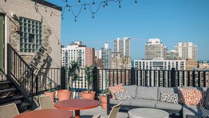 A rooftop terrace with outdoor seating, potted plants, and a city skyline view. - Luxury Designer Apartment 802| Gold Coast/Old Town (Chicago)