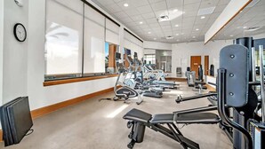 Een sportschool met trainingsapparatuur, een klok en een groot raam.