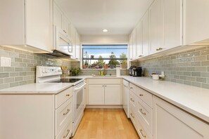Una cucina moderna con mobili bianchi, forno integrato e una finestra vista all'esterno.