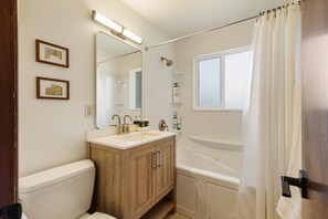 Un bagno con un mobile bagno in legno, uno specchio grande, una vasca e una finestra.