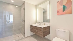 A modern bathroom with a glass-enclosed shower, a wooden vanity, and a large mirror. - Luxury Apt Back Bay | Near Prudential Center (Boston, MA)