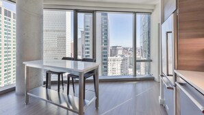 A modern apartment with a large window, a dining table, and a kitchen area. - Luxury Apt Back Bay | Near Prudential Center (Boston, MA)