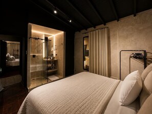 Een moderne hotelkamer met een groot bed, een douchecabine met glazen wanden en uitzicht op de stad door het raam.