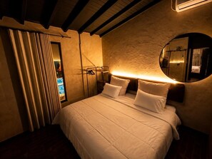 A hotel room with a large bed, a round mirror, and a view of a pool through a window. - BLACK ROSE (Medellín)