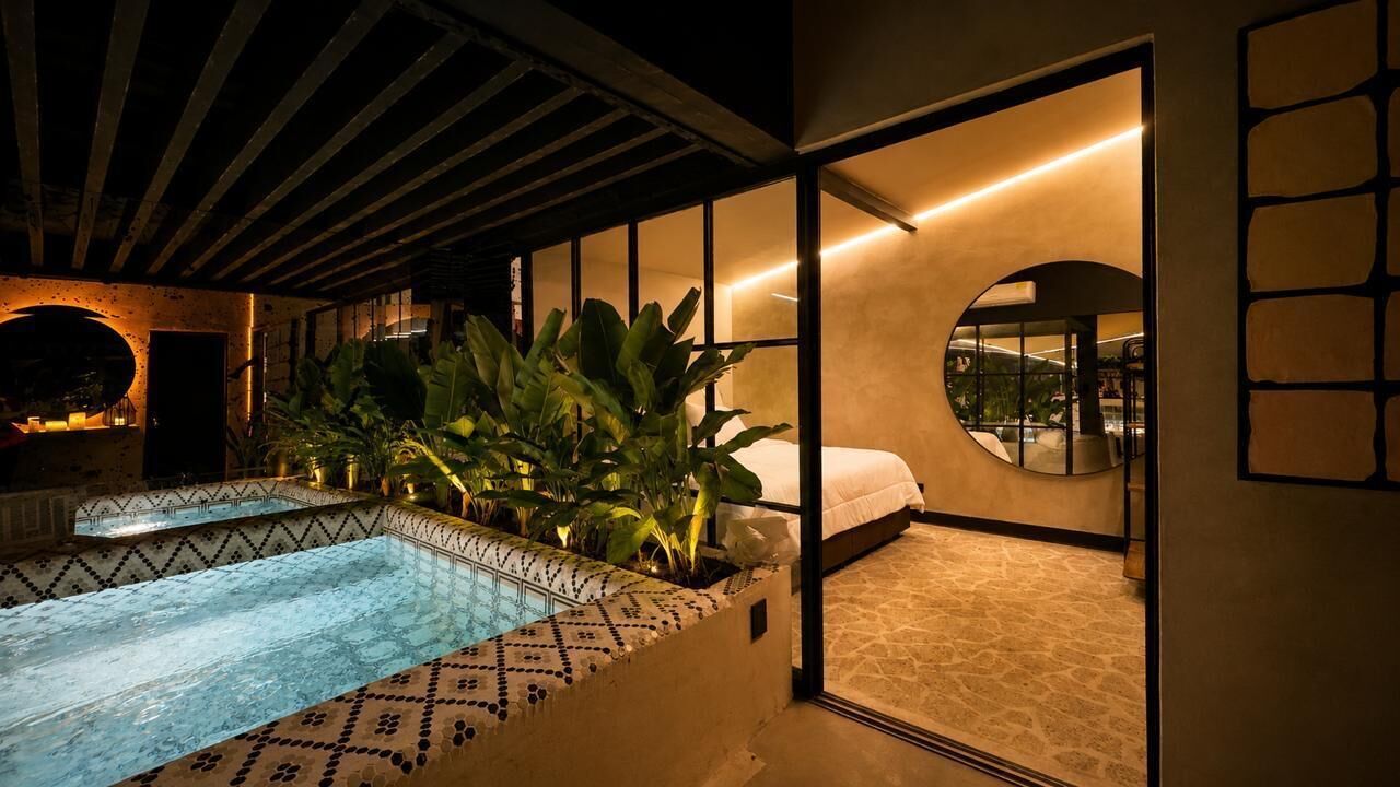 A modern hotel room with a private pool, large windows, and a circular mirror.