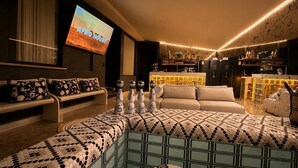 A modern living room with a large TV, a sofa, a coffee table, and a bar area.