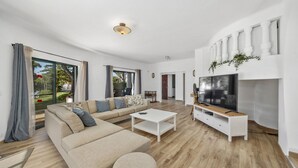 Ein geräumiges Wohnzimmer mit einer großen Couch, einem Couchtisch und einem Fernseher auf einem Holzboden.