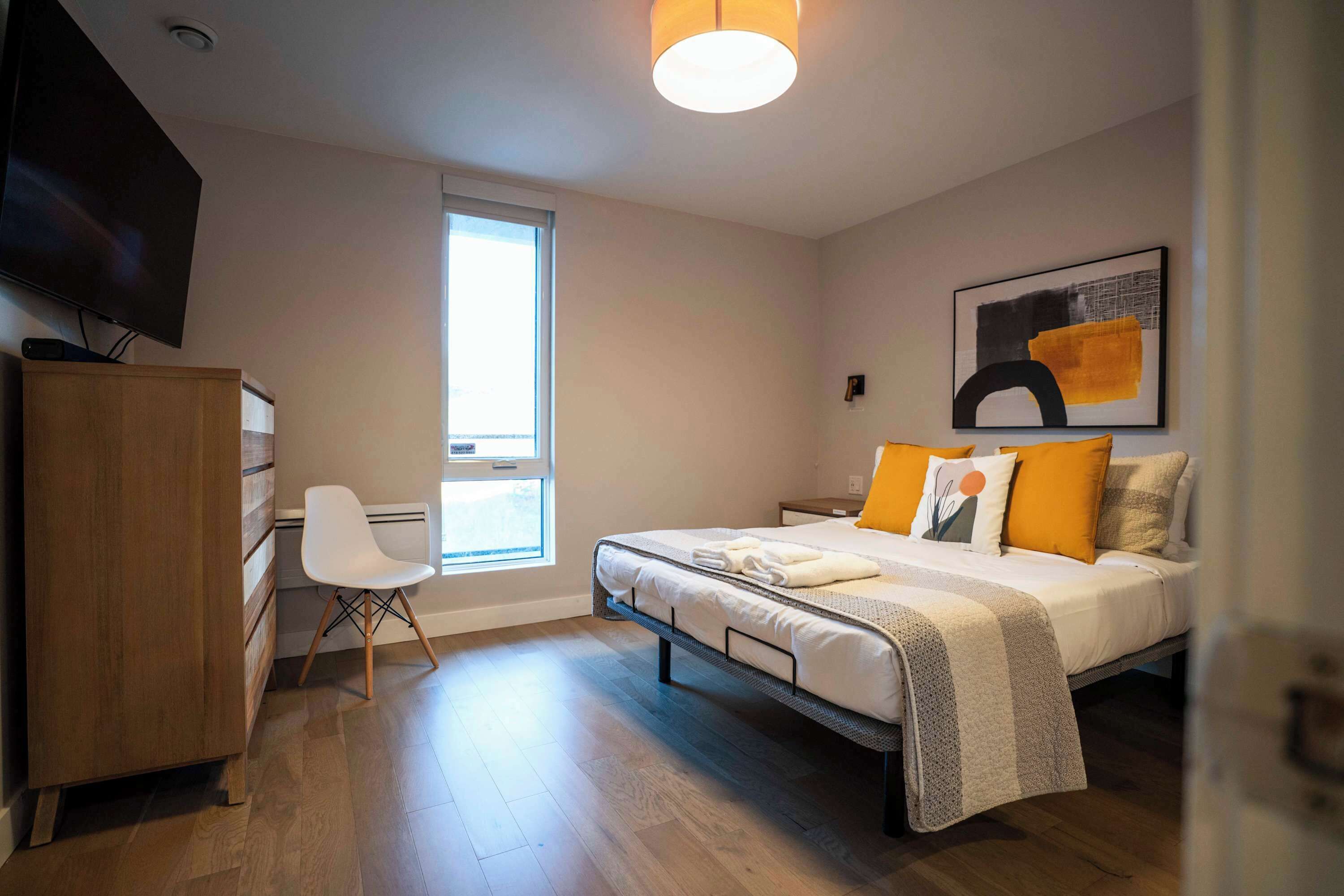 Ein modernes Schlafzimmer mit Bett, Schreibtisch, Stuhl und Fernseher.