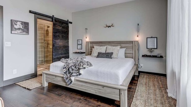 Une chambre à coucher avec un lit, un ventilateur de plafond, une cheminée et une porte-fenêtre coulissante.