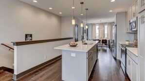 Une cuisine moderne dotée d’un îlot central, de luminaires suspendus et donnant sur l’espace repas.