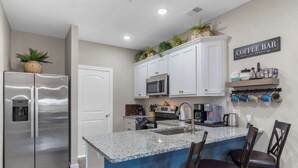 A modern kitchen with a stainless steel refrigerator, a built-in microwave, and a coffee bar sign. - Crossroads Vistas - 3BDR Condo (Branson)