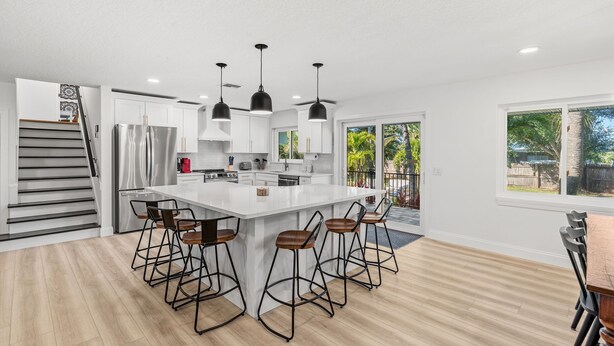 A modern kitchen with a central island, bar stools, and pendant lighting.