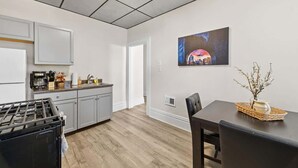 Una cocina moderna con armarios grises, una estufa negra y una zona de comedor con una mesa y sillas negras.