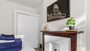 Una habitación de hotel con cama, espejo, letrero en marco, planta en maceta y puerta.