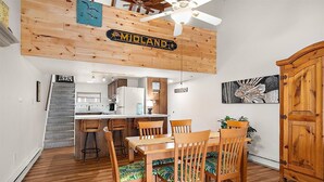 A dining area with a wooden table and chairs, a kitchen in the background, and a wooden ceiling with a 'Midland' sign. - Unique Bayfront Townhome with a Prime Location (Ocean City)