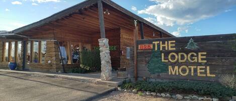 A wooden lodge with a sign reading "THE LODGE MOTEL" and a phone number "825".