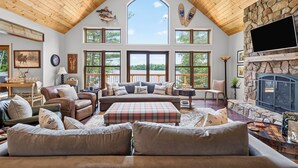 A spacious living room with a high ceiling, large windows, a fireplace, and various seating arrangements. - Gliemwood II at Clam Lake | 5BR Lakefront Retreat (Clam Lake)