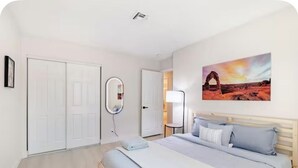 Quarto com cama, espelho e porta.