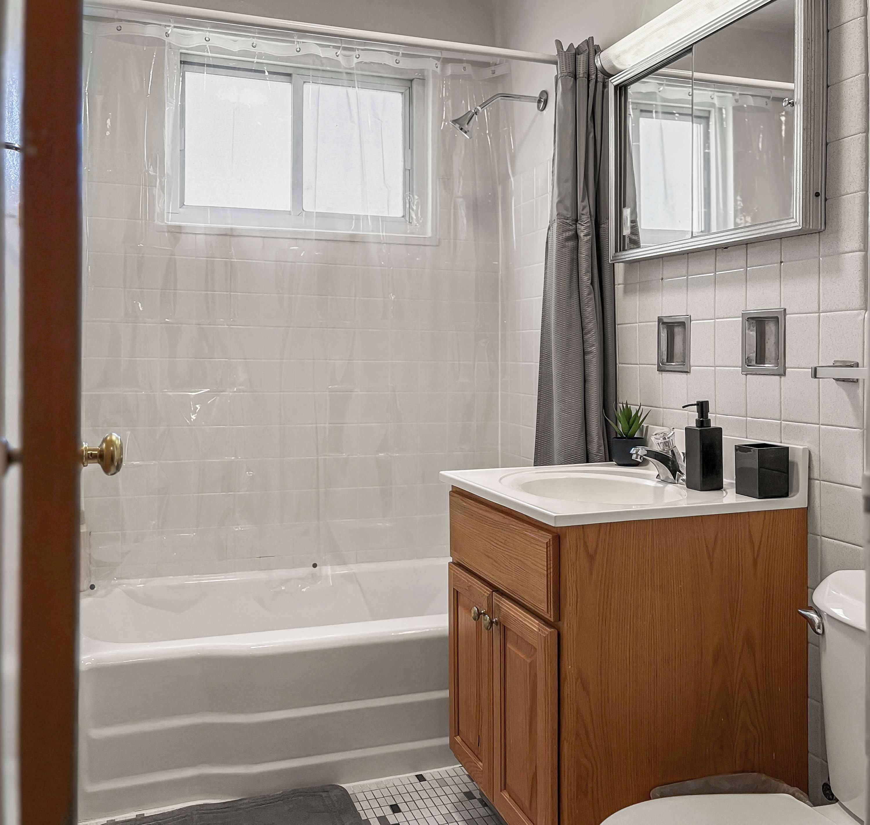 Un baño con bañera, tocador con espejo y retrete.