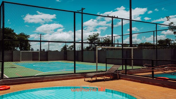 Een tennisbaan buiten met net, een zwembad en ligstoelen.