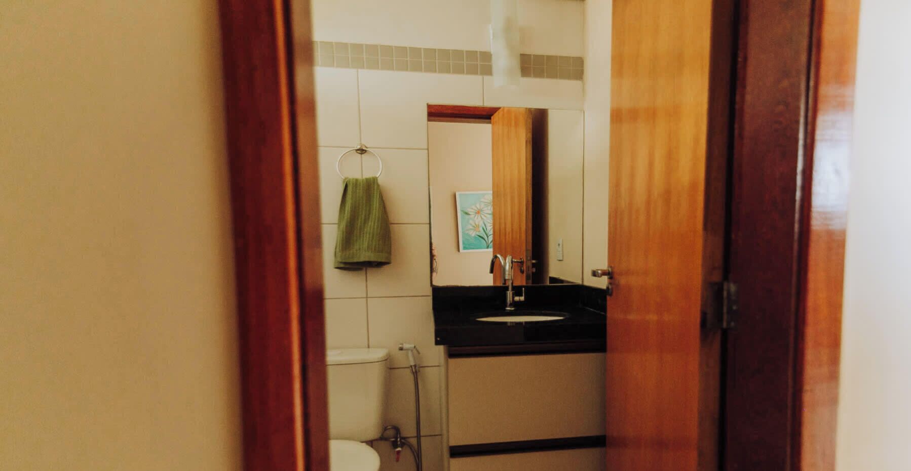 A bathroom with a toilet, sink, and towel hanging on the wall.