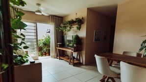 Een moderne woonkamer met een eethoek, een televisie en verschillende potplanten.