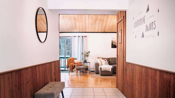 A hallway with wooden paneling, a bench, a sofa, and a wall with a motivational quote.