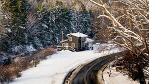 A snow-covered landscape with a house on a curved road.