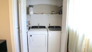 A compact laundry room with two white washing machines and a small shelf above them.
