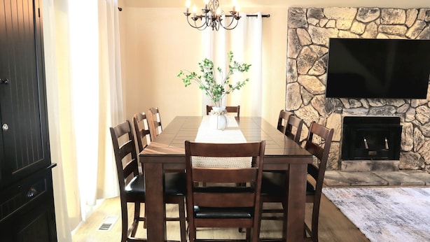 A dining area with a stone wall, a flat-screen TV, and a fireplace.