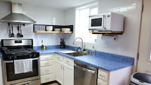 A modern kitchen with a stainless steel stove, a dishwasher, a microwave, and white cabinets.