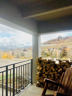 Een overdekt terras met uitzicht op een bergachtig landschap en woonhuizen.