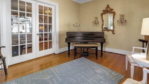 A room with a piano, a chandelier, a mirror, and a door with glass panels. - 5 Bedroom Home w/ Private Parking Near Niagara Falls (Niagara Falls)