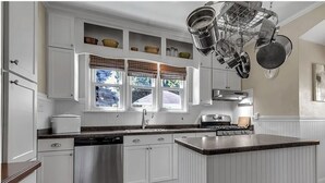 A kitchen with white cabinetry, a stainless steel dishwasher, a stove, and a hanging pot rack. - 5 Bedroom Home w/ Private Parking Near Niagara Falls (Niagara Falls)