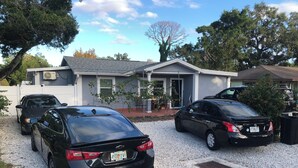 A residential driveway with two parked cars, a house with a grey roof, and a white fence. - Pleasant 1-bedroom NEW Studio 3 with NEW AC in Pinellas Park (Pinellas Park)