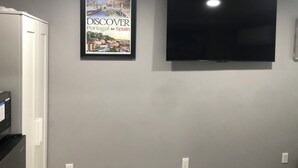 A framed travel poster of Portugal and Spain on a wall, a flat-screen TV, and a white appliance. - Pleasant 1-bedroom NEW Studio 3 with NEW AC in Pinellas Park (Pinellas Park)