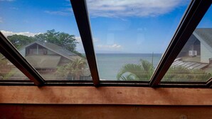 A view through a window with a wooden frame, overlooking a coastal area with houses and a clear sky. - KAHANA SPACIOUS 3 BEDROOM CONDO; BEACH ON SITE; EXCELLENT VIEWS (Lahaina)